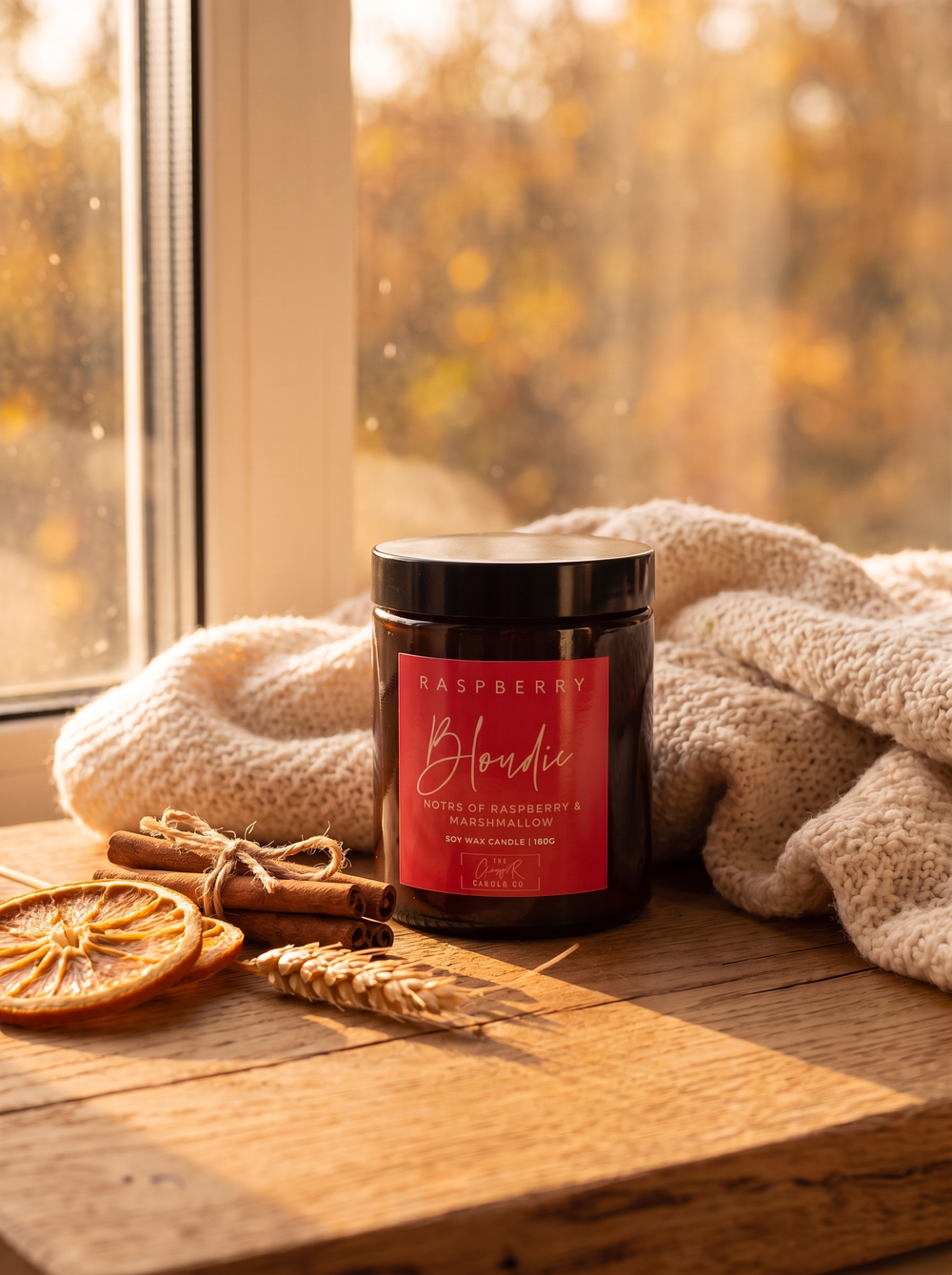 Raspberry Blondie candle styled in a cosy autumn window scene