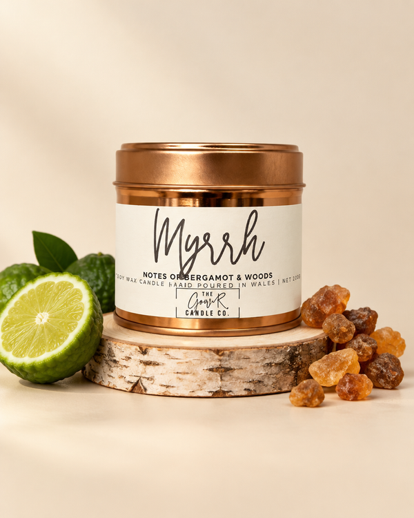 Myrrh rose gold soy candle by The Gower Candle Co. on a birch slice with bergamot and resin