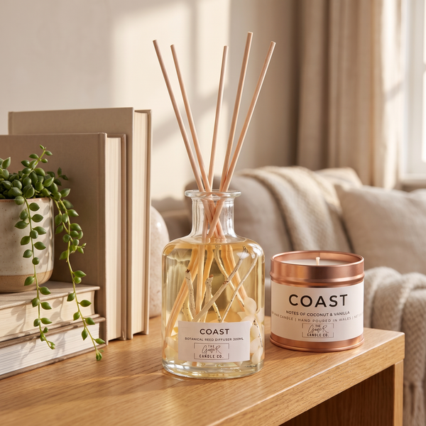 Coast botanical reed diffuser and matching candle bundle styled on a wooden table with books and a plant