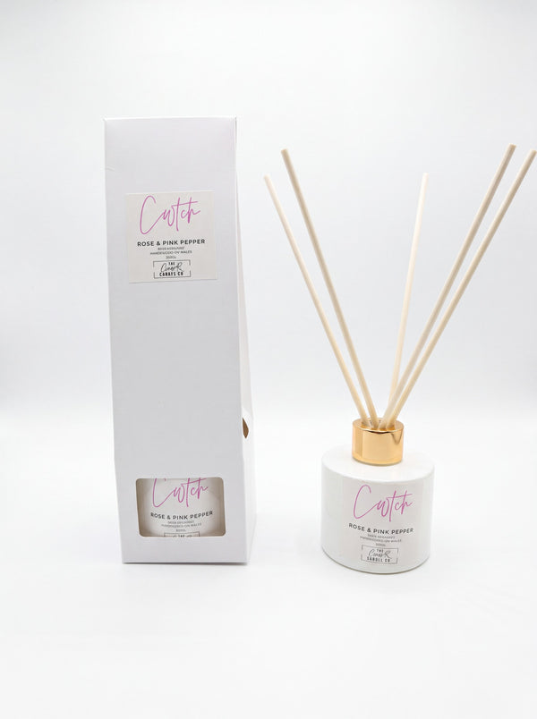 Cwtch rose and pink pepper reed diffuser with gold collar and gift box on white background, handpoured in Wales by The Gower Candle Co.